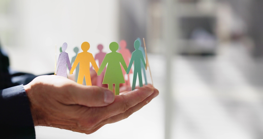 Hands holding paper people in all colours of the rainbow